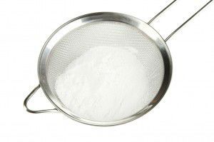 Powdered sugar in metal sieve isolated on white