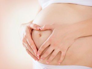 Pregnant Woman holding hands in a heart shape on her baby bump