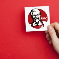 LONDON, UK – February 21st 2018: Hand holidng aKFC fast food sign. KFC is an american fast food company that specializes in chicken