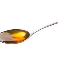 A spoon of honey over white background