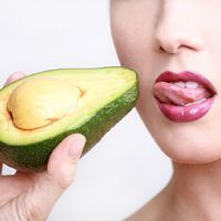 Beautiful young woman holding avocado