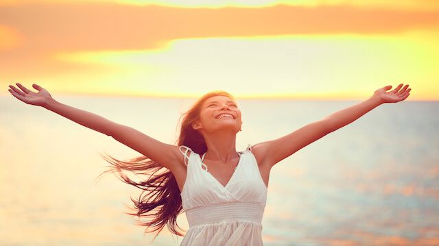 Free happy woman praising freedom at beach sunset