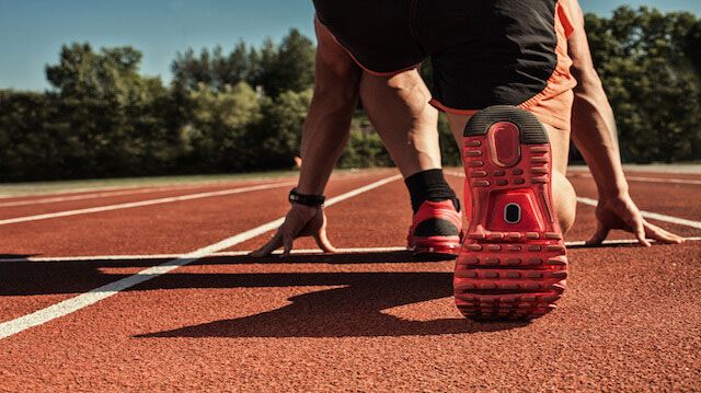 young muscular athlete is at the start of the treadmill at the stadium