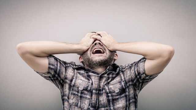 portrait one sad man standing near a wall and covers his face