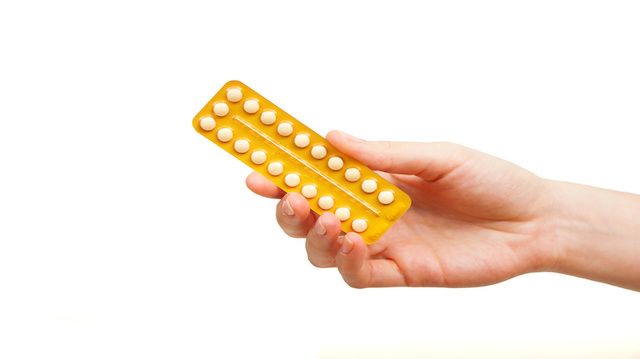 woman holding birth control pills