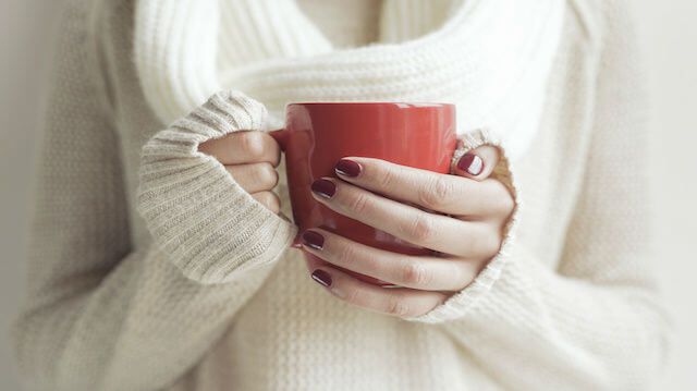 Cup of tea or coffee in female hands.