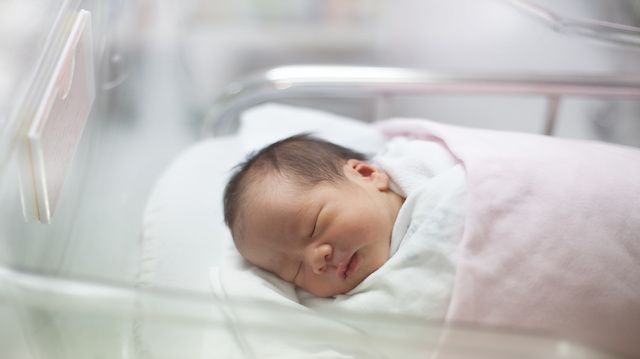 new born infant asleep in the blanket in delivery room