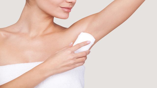 Staying fresh. Cropped image of beautiful young woman wrapped in towel standing against grey background