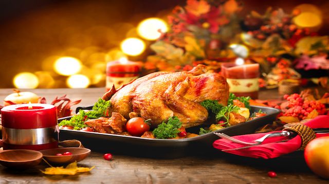 Thanksgiving dinner table served with turkey, decorated with bright autumn leaves