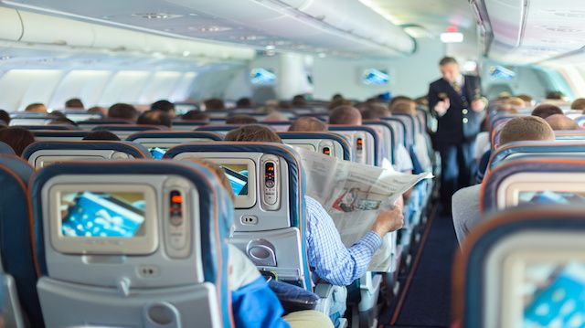 Steward and passengers on commercial airplane.