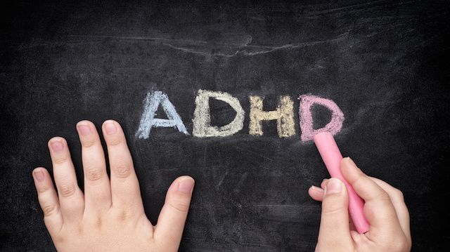 Child writing ADHD on blackboard