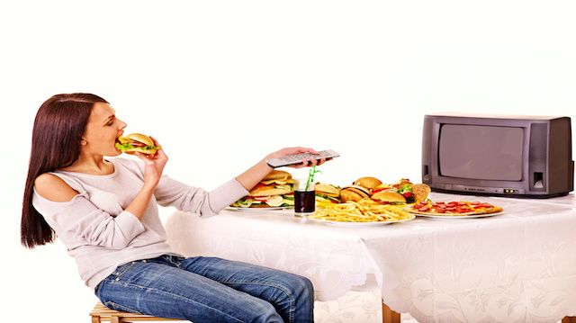 Woman eating fast food and watching TV.