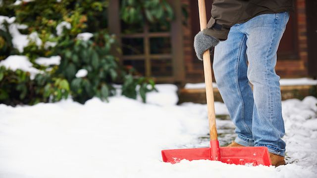 Man Clearing Snow From Path With Shovel