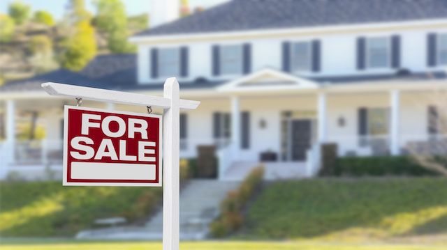 Home For Sale Real Estate Sign in Front of Beautiful New House.