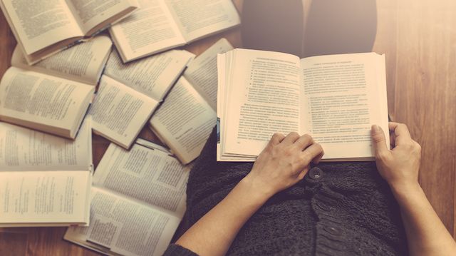 Woman reading a few books on the floor