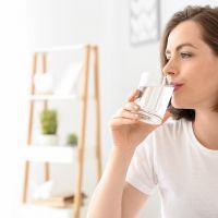 Morning of beautiful young woman drinking water in bedroom