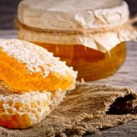 Honey background. Sweet honey in the comb, glass jar. On wooden background.