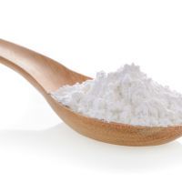 Pile of white wheat flour in wooden spoon