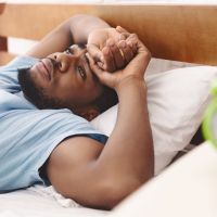 Black man in bed suffering from insomnia and sleep disorder