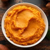 Mashed Sweet Potatoes in white bowl on wooden rustic table. Healthy food