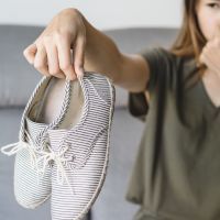 Young woman holding a pair of smelly shoes