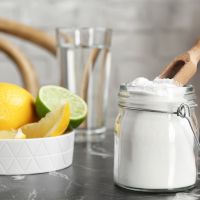 Jar with baking soda and lemons on table indoors