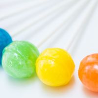 Rainbow design of sweet colorful lollipops against white background