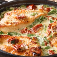 Italian chicken breast with sun-dried tomatoes and spinach in cheese sauce close-up in a pan. horizontal