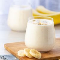 Vegan banana and oatmeal smoothie in glass jar on the light background.